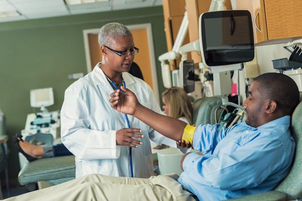 Photo of man and woman. Giving blood in hospital setting.