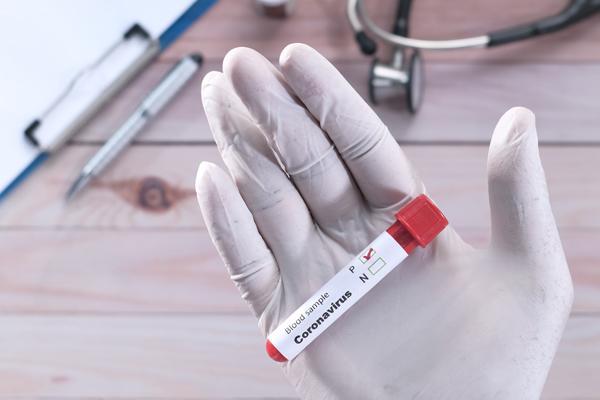 Photo of gloved hand holding vile of blood.