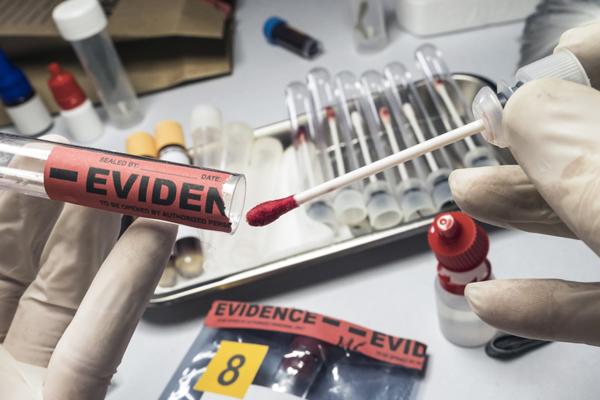 Photo of swab with blood being inserted into evidence tube.