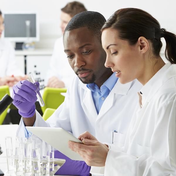 Photo of lab scene. Two people reviewing software demo on tablet.