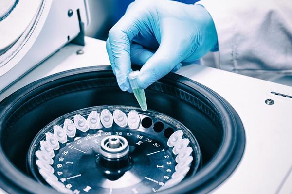 Close up of a chemist using a centrifuge in lab.